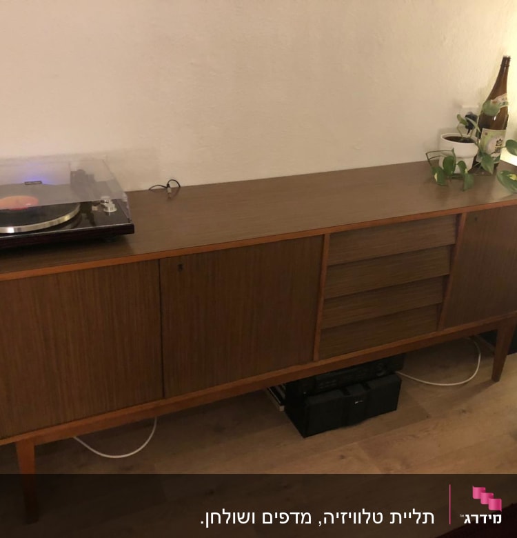 פטיפון על שידה מעץ עם צמחים ובקבוק